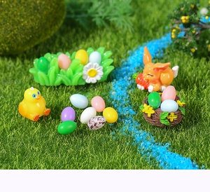 Miniature Easter resin figurines with rabbit, chicks and colorful eggs on artificial turf