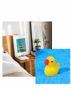 Detailed view of a small yellow duck resin ornament placed on blue decorative sand