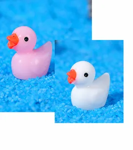 Detail of pink and white resin duck figurines on blue sand for micro landscape decor