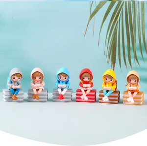 Close-up of miniature raincoat girl figurines sitting on book bases in six bright colors