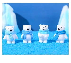 Detailed view of four polar bear figurines with blue scarves on a winter snow landscape