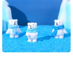 Detailed view of polar bear figurines with blue scarves on simulated ice and blue sand