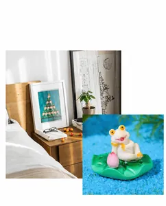 Detail view of cute resin frog figurine on lily pad with pink lotus flower for fish tank
