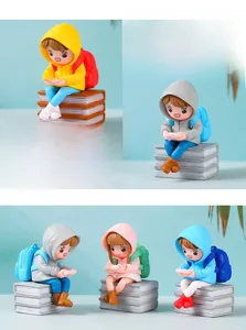 Macro detail of miniature girls in raincoats sitting on books for micro landscape decor