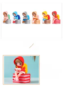 Detail of red resin figurine girl with backpack reading books in raincoat