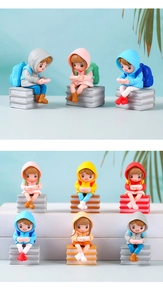Detailed macro view of creative PVC figurines wearing hoodies and gaming on book bases