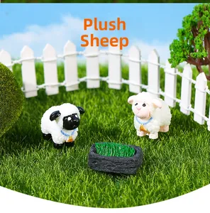 Figurines de moutons miniatures en résine avec colliers bleus à côté d'une auge à fourrage