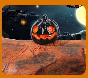 Close-up of a black resin Halloween pumpkin ornament with orange face details on wood