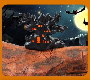 Detailed view of resin haunted house ornament with glowing orange windows for Halloween decor