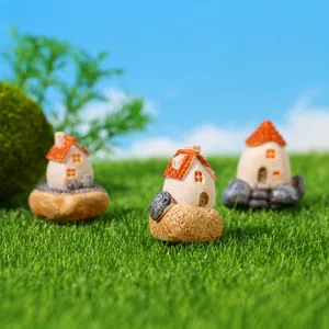 Dettaglio di tre casette in resina con tetti arancioni su base in finta erba per giardini
