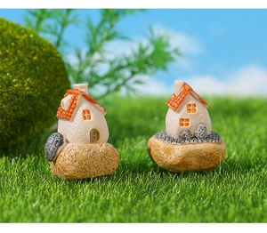 Macro shot of miniature resin country cottages on green moss for micro landscape decor
