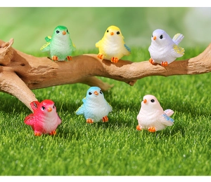 Detail of six colorful resin bird figurines on mossy wood for micro landscape decor