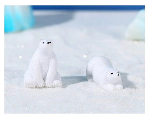 Miniature polar bear figurines in sitting and lying poses on white sand arctic scenery