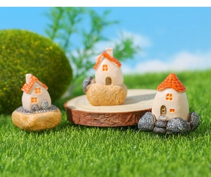 Detailed view of three miniature fairy garden houses with orange roofs on mossy logs