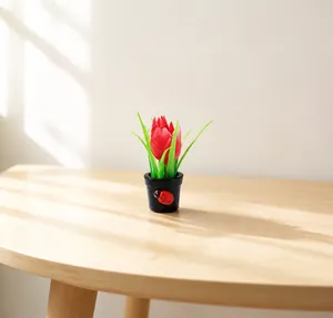 Dettaglio di mini tulipano artificiale con fiore rosso e coccinella su vaso nero