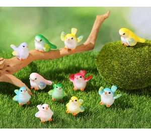 Detailed view of colorful resin bird figurines on moss and grass for micro landscapes