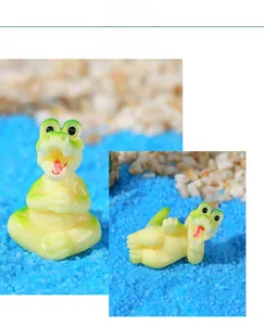 Macro view of cute resin crocodile figurines on blue sand for aquarium DIY landscape