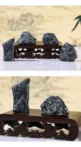 Close-up of textured black landscape stones with a carved wooden display base