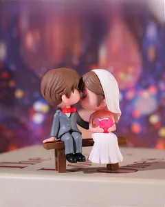 Close-up of romantic cartoon wedding couple figurines sitting on a long wooden bench