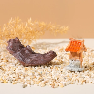Miniature resin driftwood and orange well ornament on pebbles for aquarium decor