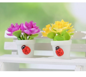 Miniature dollhouse potted flowers with ladybug motif on a white wooden bench