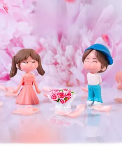 Detail of cute miniature resin couple dolls with girl in pink dress and blue hat boy