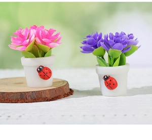 Detail of miniature dollhouse potted plants with pink and purple flowers and ladybug decor