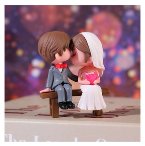 Close-up of romantic cartoon wedding couple figurines sitting on a miniature bench