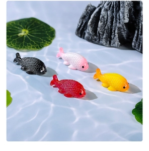 Macro top view of colorful resin goldfish figurines on a blue water ripple background