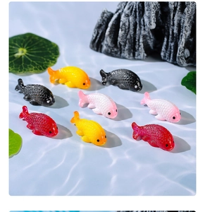 Detail of colorful resin goldfish miniatures on blue water ripples for aquarium decor