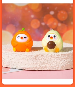 Macro shot of cute resin chick figurines in orange and avocado outfits on stone stand