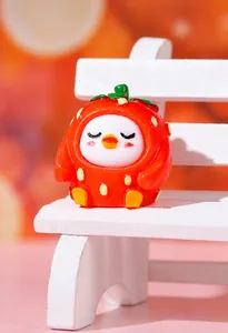 Macro shot of resin strawberry chick figurine on a white miniature stool with warm background