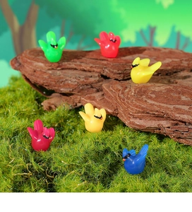 Close-up of five colorful miniature resin hummingbird figurines on moss and bark