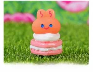 Macro shot of 3D orange bunny resin charm on a pink macaroon base for DIY crafts