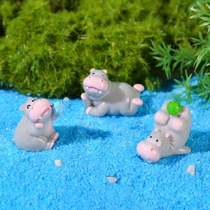 Trois adorables figurines d'hippopotame en résine sur mousse et sable bleu paysage