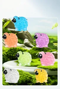 Détail macro de sept moutons colorés en résine dans un paysage de mousse verte