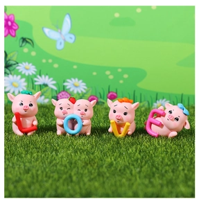 Close-up of four cute pink resin pigs holding colorful letters spelling LOVE for decor