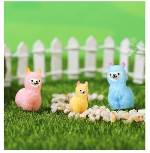 Three colorful miniature alpacas figurines set on a moss landscape with mini fence