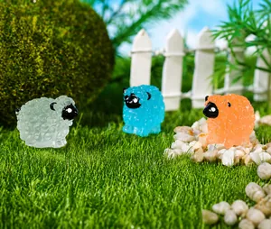 Détail de trois figurines de moutons miniatures en résine sur gazon avec clôture