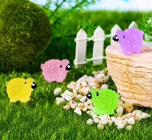 Mini figurines de moutons en résine de quatre couleurs sur un décor de jardin d'herbe