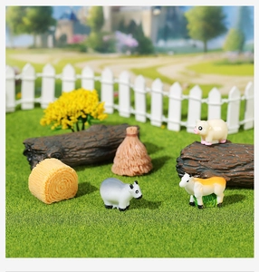 Macro view of miniature farm animal resin figurines with haystack decor in terrarium