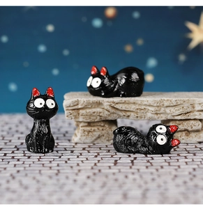 Detailed macro view of three miniature resin black cats on a decorative stone bridge