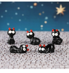 Detail view of five miniature black resin cats with big white eyes and red ears for garden DIY