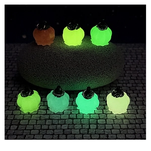 Luminous pumpkin charms glowing in multiple colors on textured stone in a dark scene