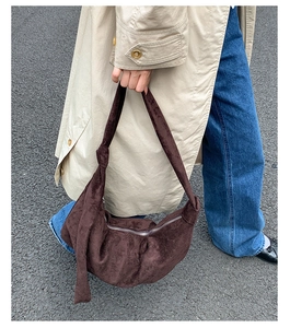 Macro shot of dark brown suede dumpling bag with elegant knot detail on the shoulder strap
