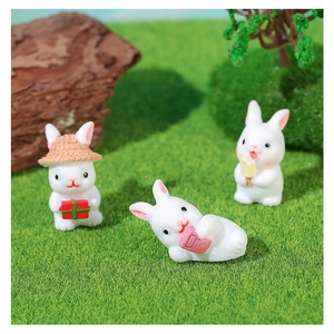 Close-up of three cute resin bunnies with gift boxes and ice cream in miniature garden