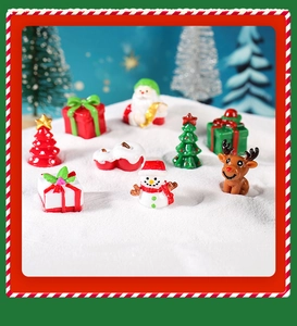 Makroansicht kleiner Harz-Weihnachtsfiguren mit Weihnachtsmann, Schneemann und Rentier im Schnee