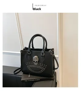 Detail of black leather tote bag featuring silver rhinestone skull and metal studs