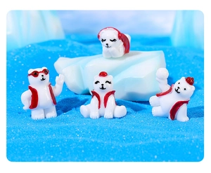 Set of four miniature polar bear resin figures with red accessories on faux ice and sand
