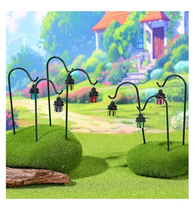Close-up of colorful miniature lanterns with black metal hooks on moss garden landscape